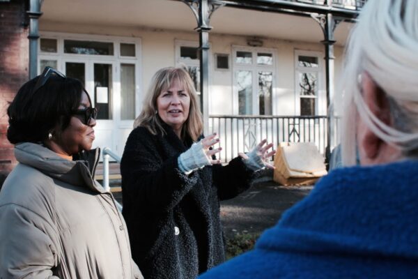 women standing in group one expressing with her hands in front of building with veranda
