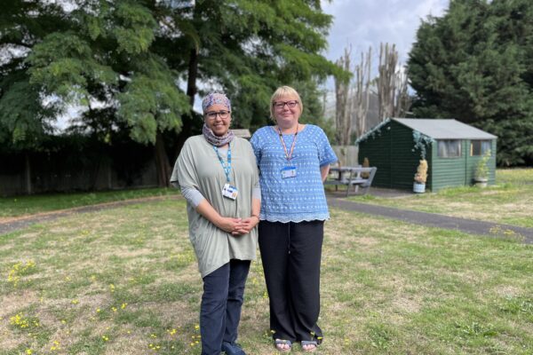 two NHS workers standing and smiling in garden
