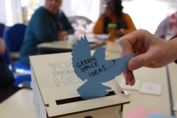 posting bird shaped note into wooden bird box in meeting